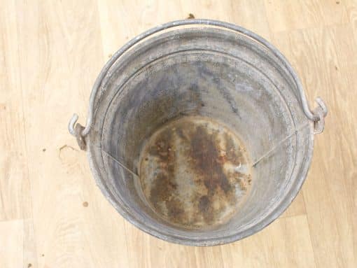 Weathered galvanized steel bucket with rust, sturdy handle, and unique character for everyday use.