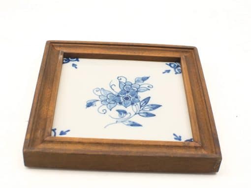 Elegant floral ceramic tile in a rustic wooden frame for vintage home decor.