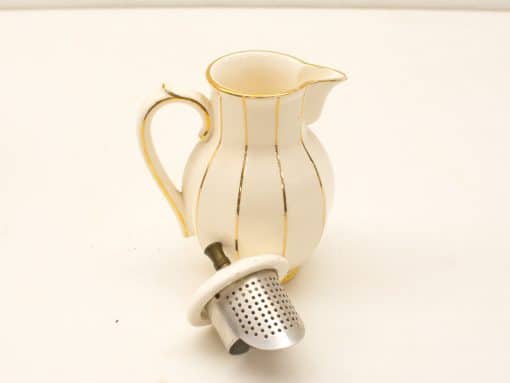 Elegant ceramic pitcher with gold accents and removable strainer for stylish serving.