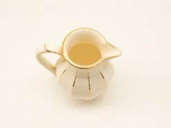 Elegant cream ceramic pitcher with golden accents, perfect for serving beverages stylishly.