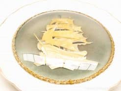 Elegant decorative plate featuring a detailed sailing ship against a grey-blue background.