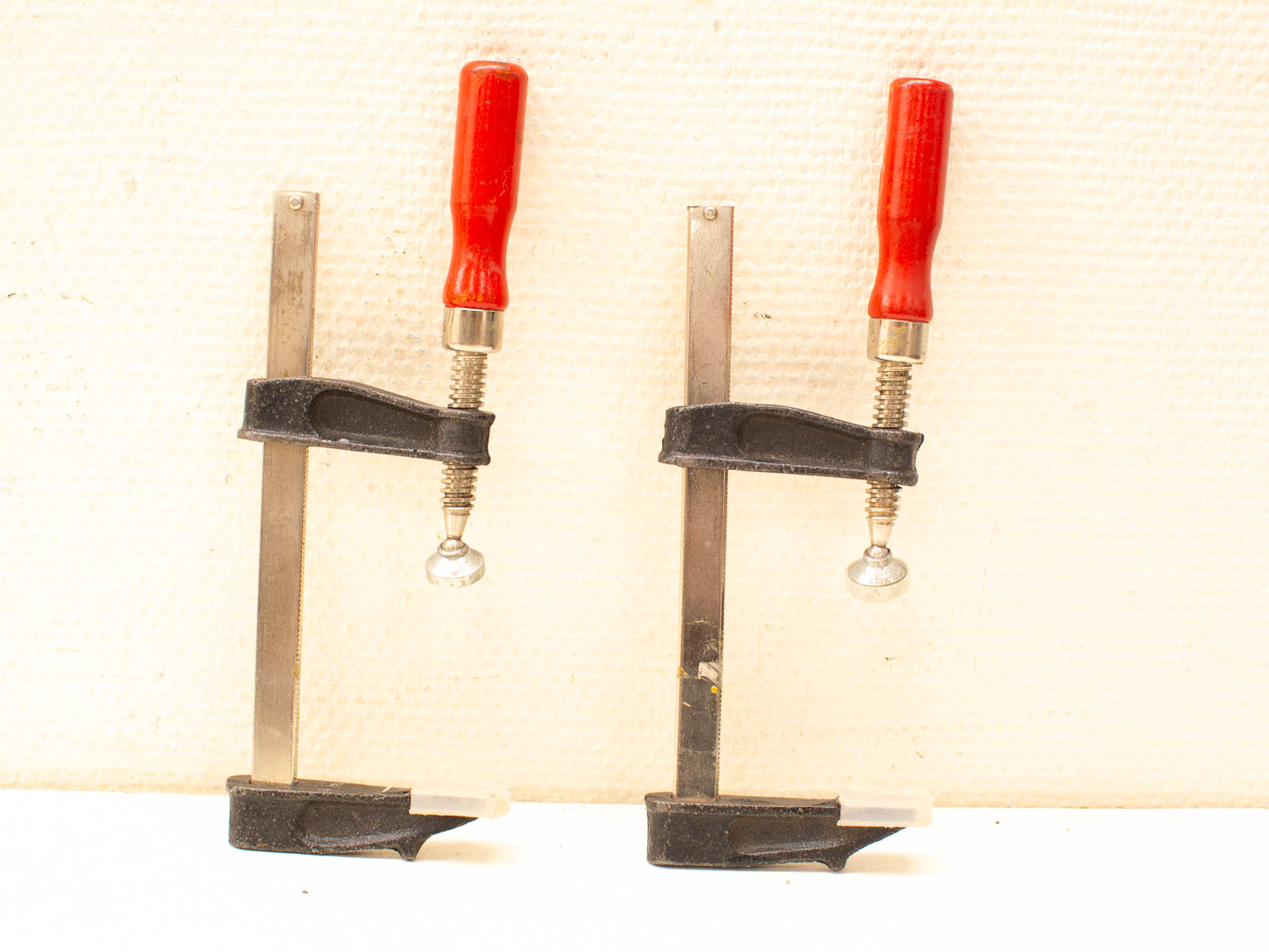Durable vintage metal clamps with red handles, perfect for woodworking and metalworking projects.
