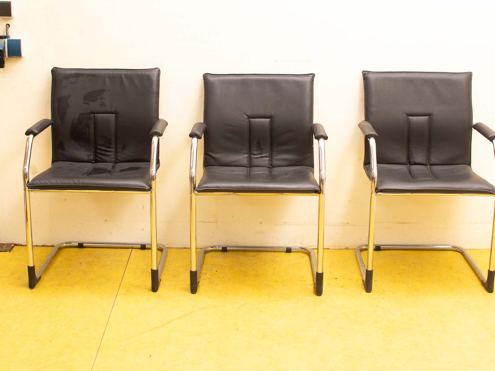 Modern black chairs on vibrant yellow flooring against a light wall, perfect for contemporary spaces.