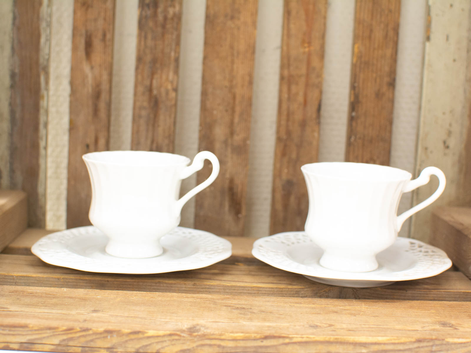 Elegant white teacups and saucers on rustic wood, perfect for a cozy tea time.