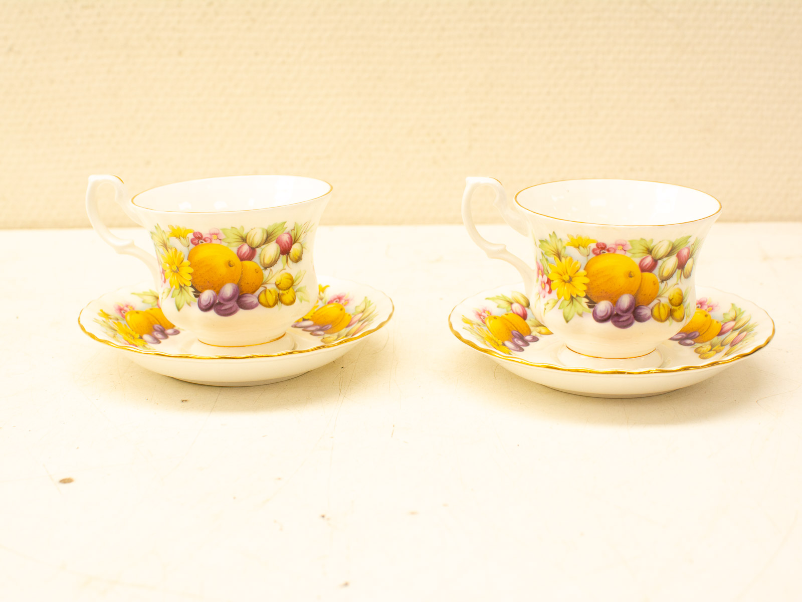 Elegant vintage teacups and saucers with vibrant floral and fruit designs for delightful tea occasions.
