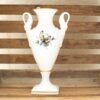 Elegant porcelain vase with bird motifs and gold trim, beautifully displayed against rustic wood.