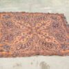 Handwoven vintage rug with warm orange and brown hues, featuring intricate floral patterns.