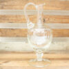 Elegant glass pitcher on rustic wood, perfect for serving or as a decorative centerpiece.