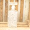 Elegant glass decanter with ornate stopper on rustic wood, perfect for home decor.