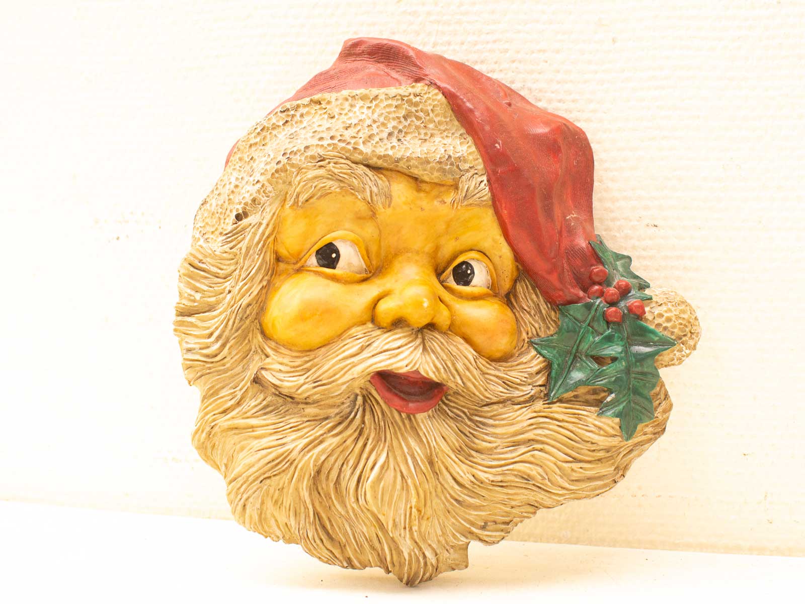 Whimsical Santa Claus with rosy cheeks, cheerful smile, and festive holly for Christmas spirit.