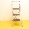 Stylish three-step ladder on bright yellow floor, ideal for home improvement tasks.