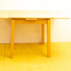 Stylish light wood dining table with drawer and extendable top for modern spaces.