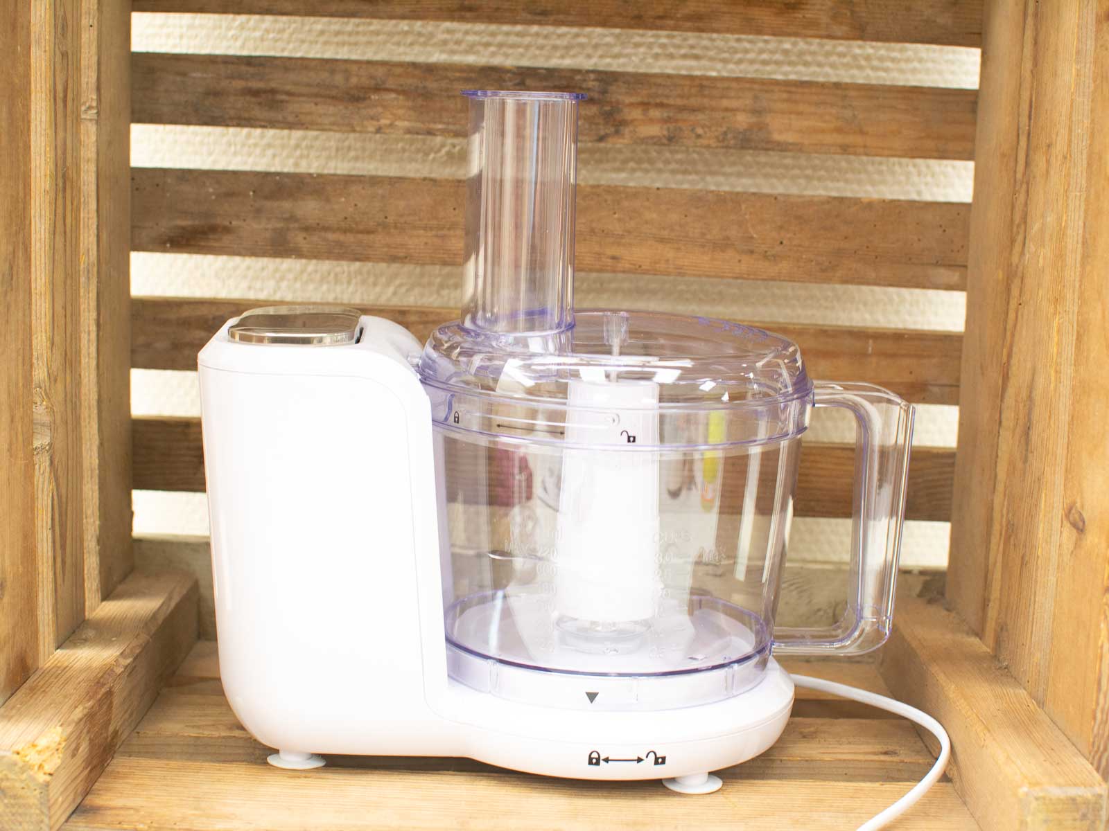 Sleek white food processor with transparent bowl on rustic wooden background, perfect for modern kitchens.