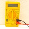 Yellow digital multimeter with test leads for voltage, current, and resistance measurements.
