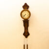 Elegant wooden wall clock with pendulums and Roman numerals, perfect for vintage decor.