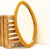 Rustic oval mirror on weathered wooden crate adds vintage charm to your decor.