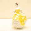Elegant porcelain figurine of a woman in a vibrant yellow gown, showcasing exquisite craftsmanship.