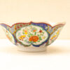 Vibrant hand-painted porcelain bowl with scalloped edges and floral designs, perfect for decor or serving.
