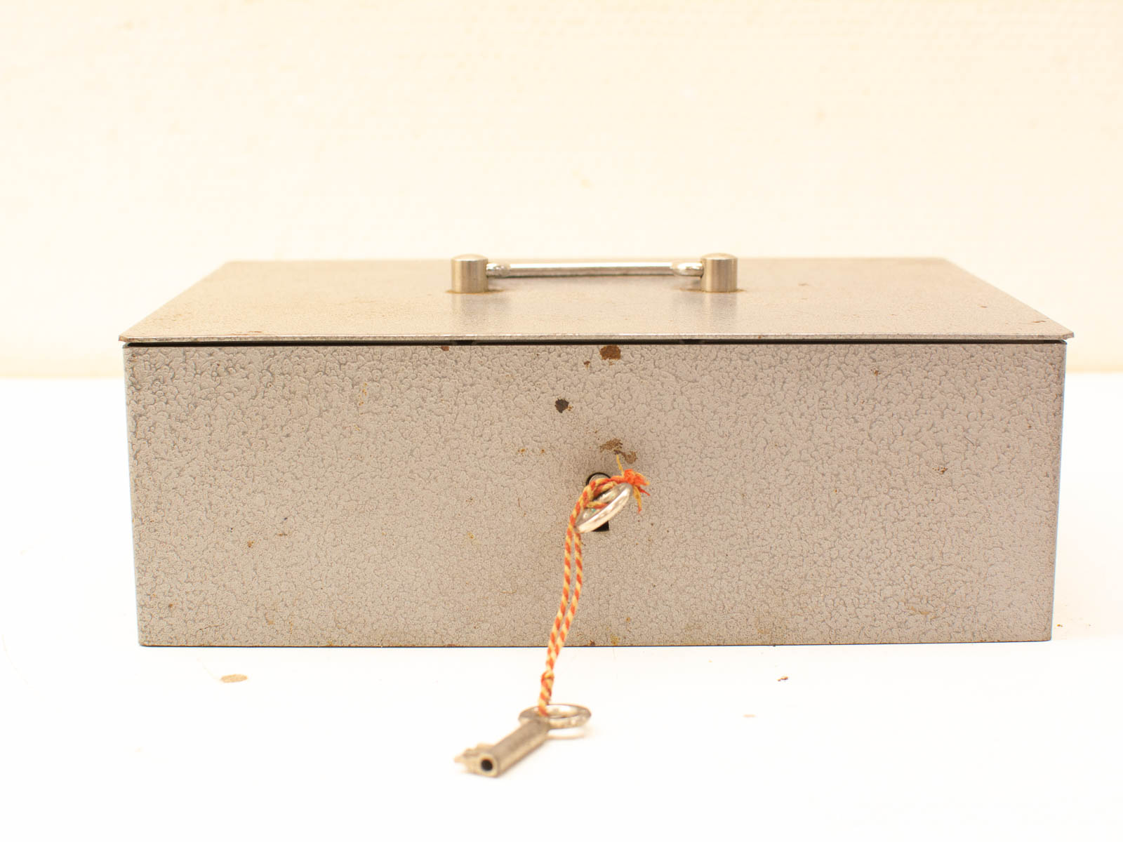 Vintage metallic storage box with handle, keyhole, and textured surface for timeless charm.