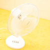 Vintage white table fan on a vibrant yellow surface, perfect for stylish indoor cooling.