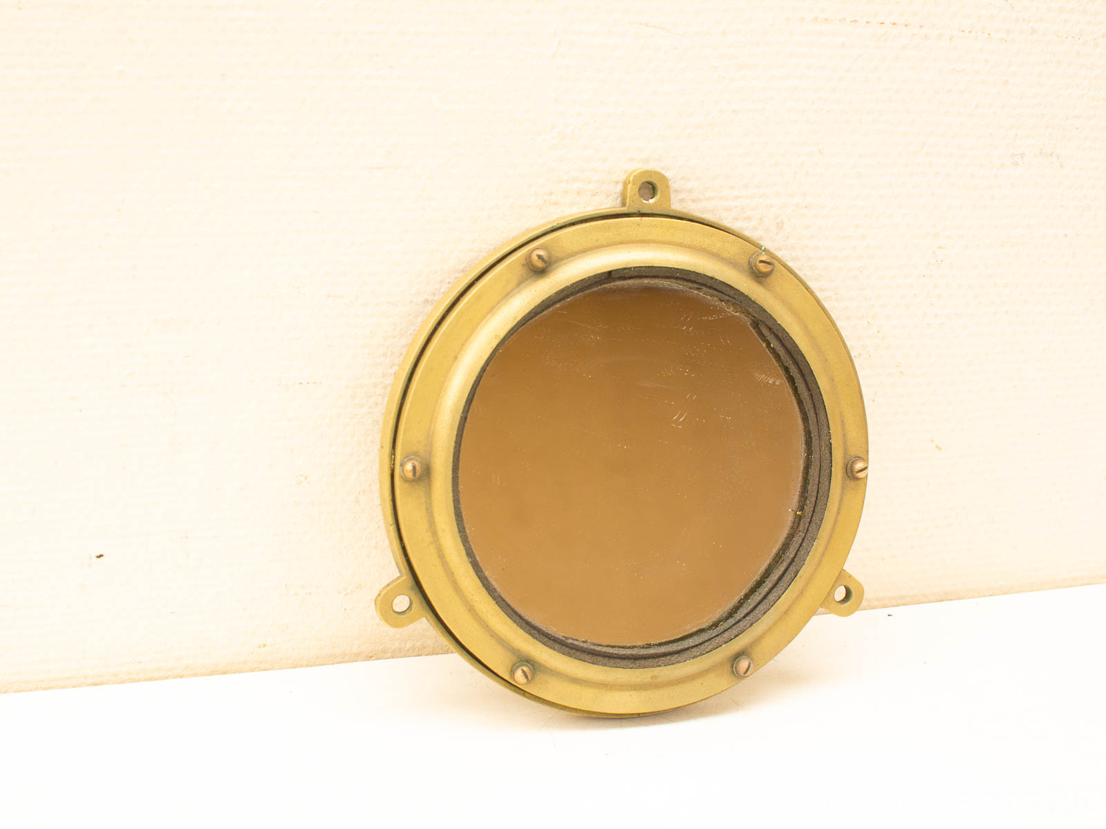Vintage brass porthole: a charming nautical decor piece for homes or ships.