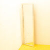 Elegant corner mirror enhances a bright room with yellow floor and soft cream walls.