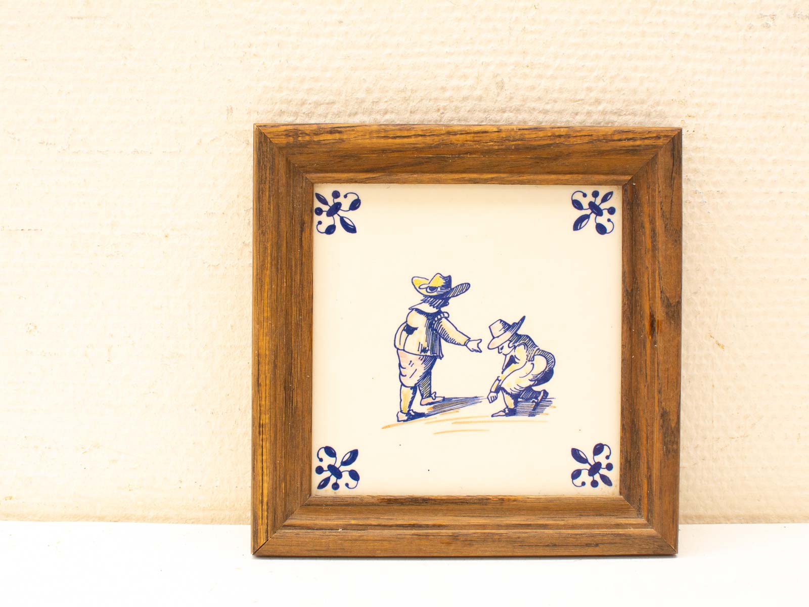 Vintage ceramic tile of playful children in a rustic frame, adding nostalgic charm to decor.