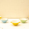 Colorful vintage pastel bowls arranged on white, highlighting handcrafted charm and playful elegance.