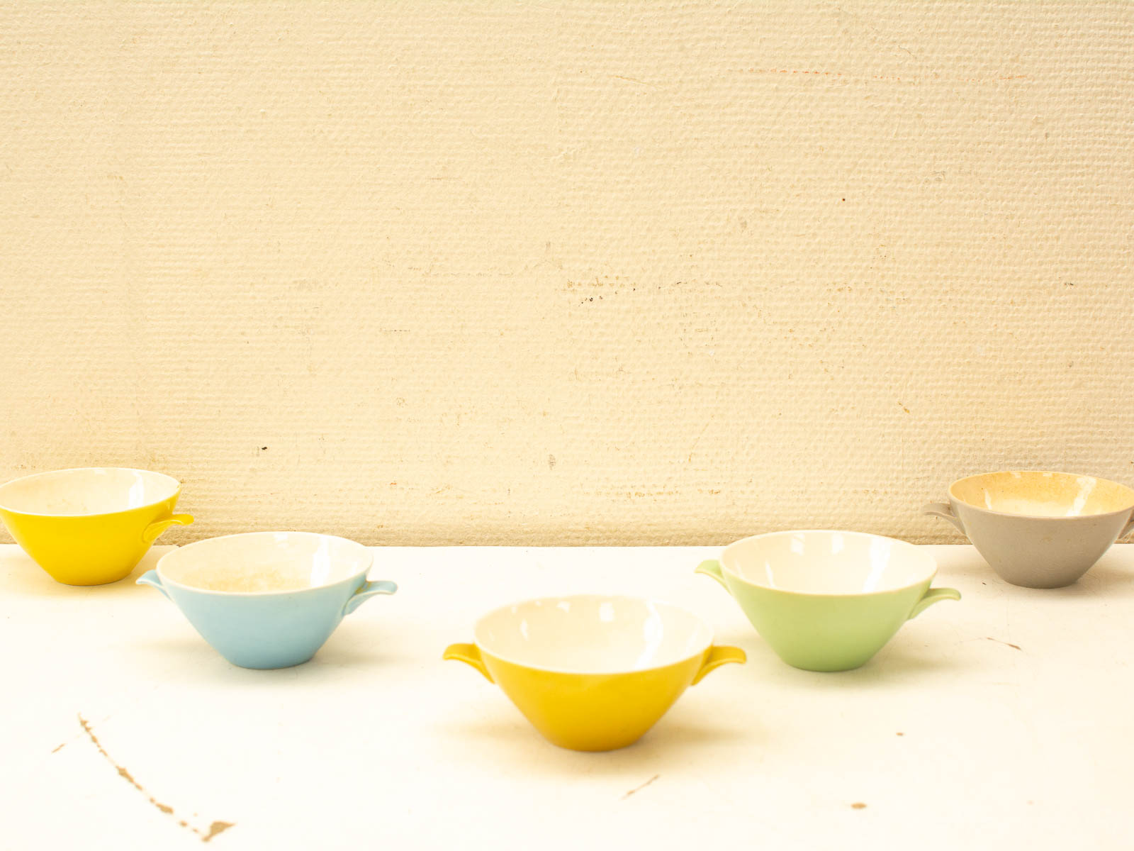 Colorful vintage pastel bowls arranged on white, highlighting handcrafted charm and playful elegance.