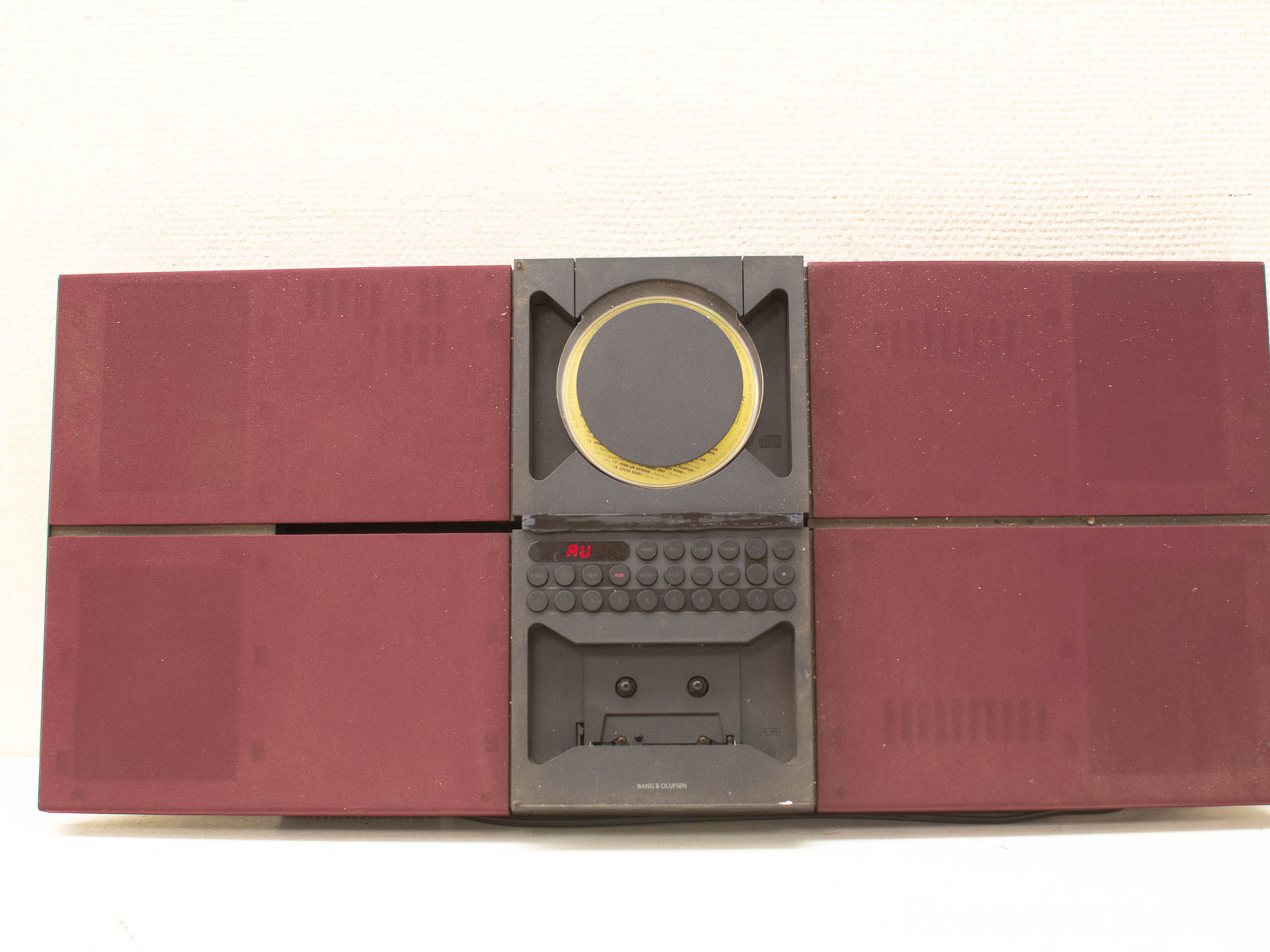 Vintage maroon stereo with gold accents, featuring integrated speakers and CD player from the late 20th century.