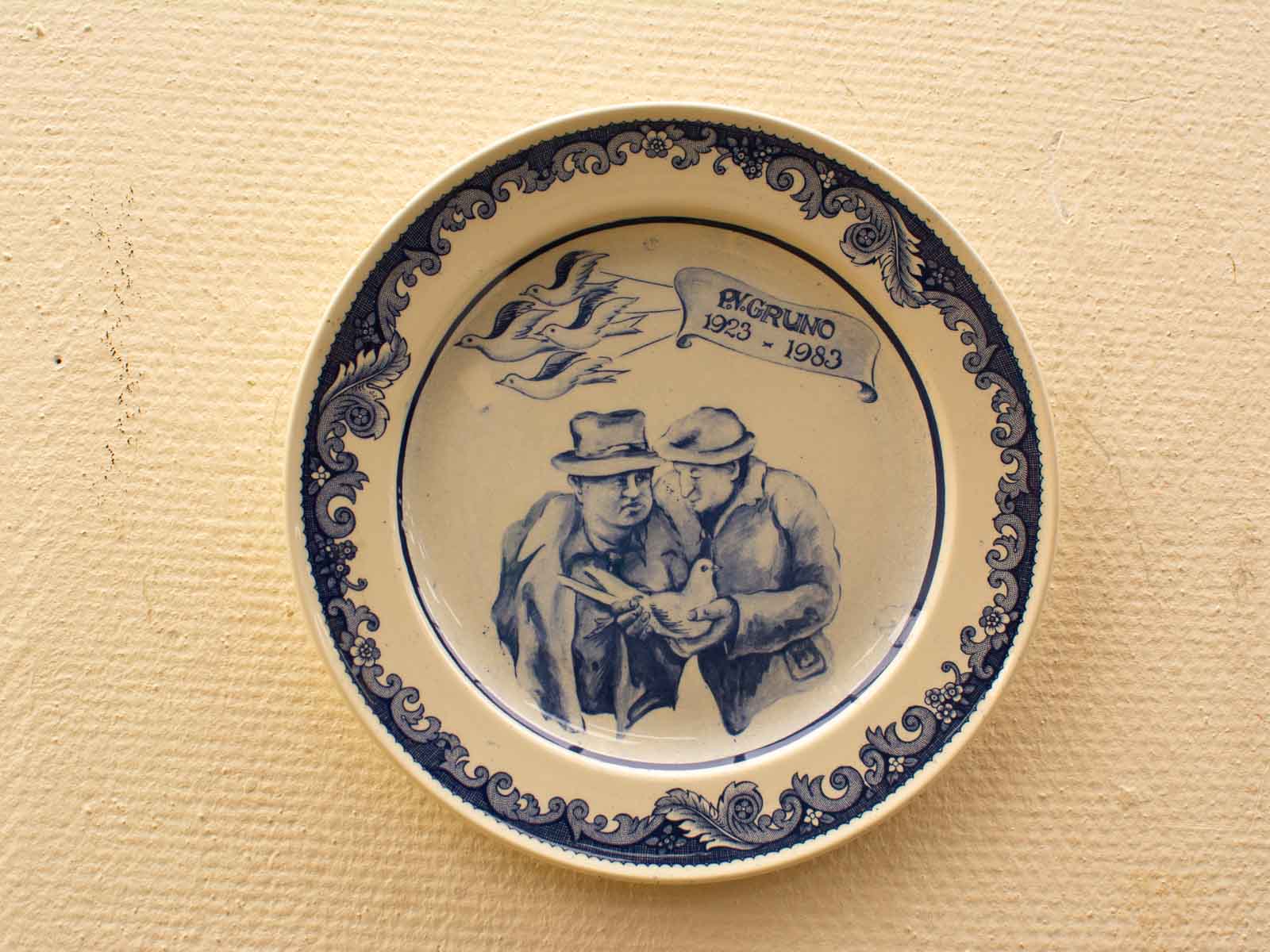 Vintage decorative plate with men conversing, floral designs, and birds by A. Gruno (1923-1983).