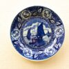 Traditional blue-white porcelain plate featuring nautical scene and floral details, celebrating maritime history.