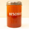 Vintage orange Beschuit glass container with silver lid, perfect for Dutch biscuit storage and kitchen decor.