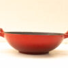 Red ceramic cooking pot with sturdy handles and non-stick dark gray interior, perfect for various culinary tasks.