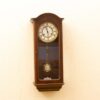 Elegant vintage wooden clock with Roman numerals and visible pendulum, perfect for any interior.