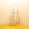 Aluminum step ladder with non-slip steps in a warm-toned utility room.