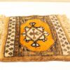 Handwoven orange rug with intricate geometric patterns, traditional motifs, and fringed edges.