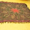 Traditional handwoven textile with intricate star motif, vibrant red and gold hues on a yellow background.