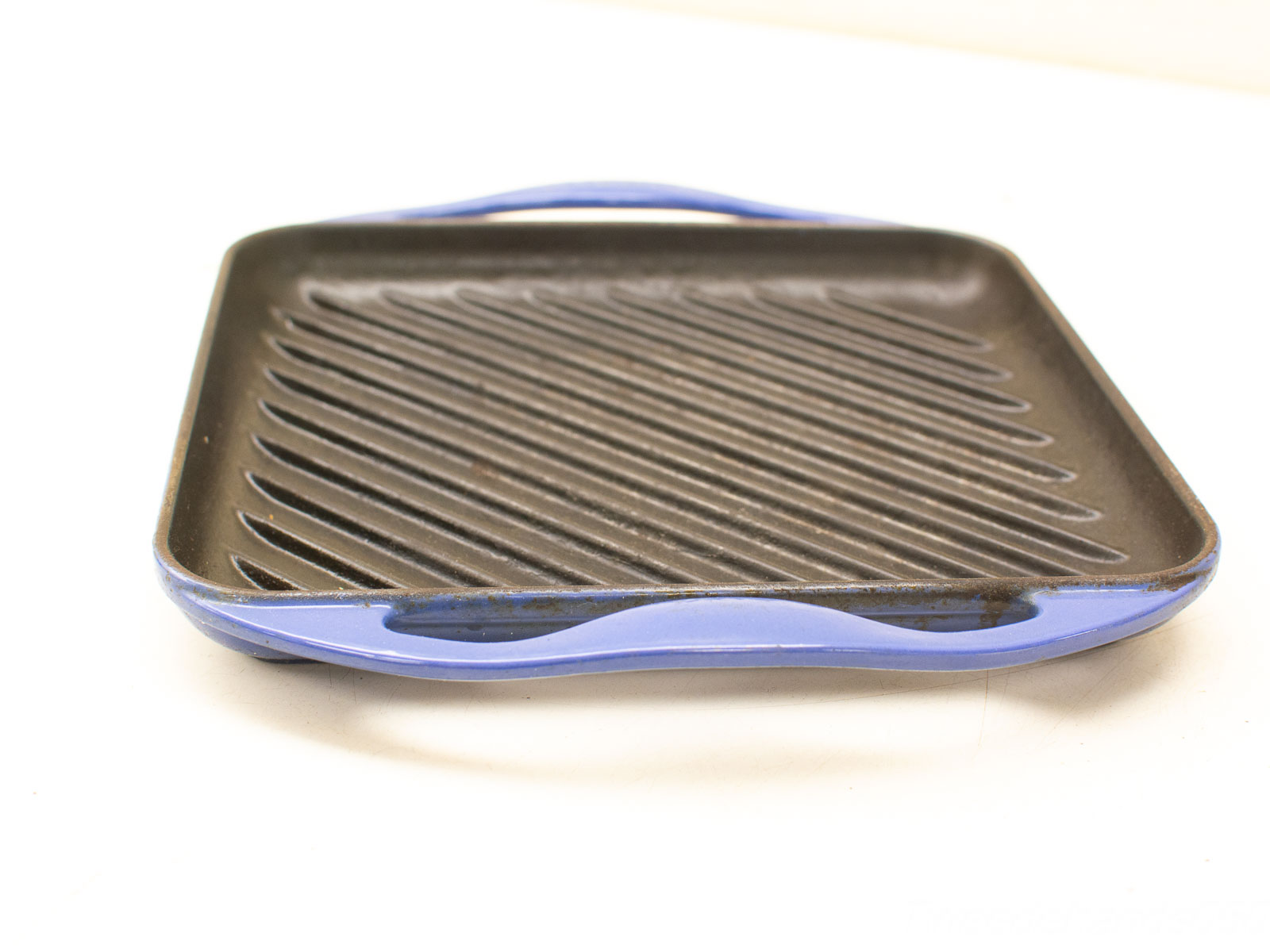 Vintage grill pan with blue handles, ideal for perfect grilling and easy cleanup.