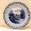 Charming blue and white plate featuring a cozy countryside house and elegant floral designs.