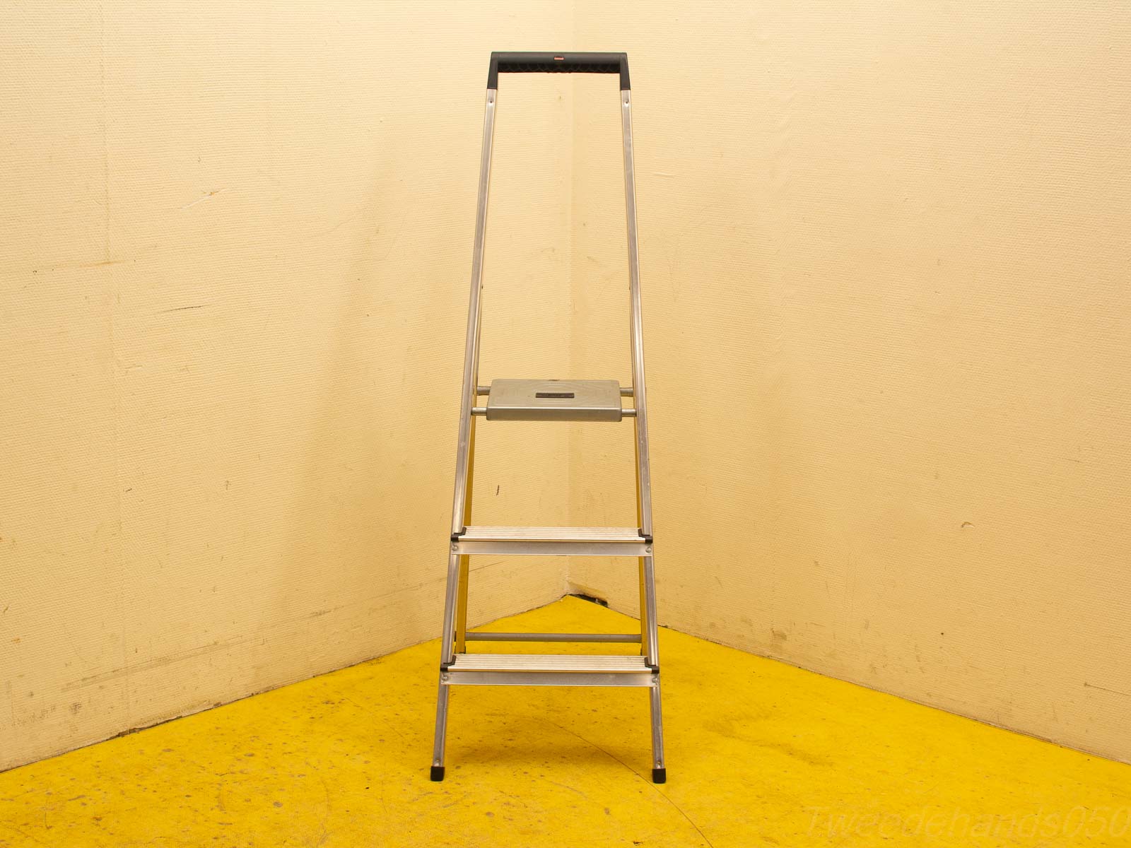 Stijlvolle aluminium ladder tegen een crème muur, ideaal voor huis- en kluswerk.