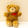 Adorable secondhand teddy bear with a red ribbon, perfect for hugs and nostalgic memories.