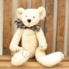 Cozy cream teddy bear with a playful plaid bow tie, perfect for any childs room.