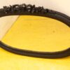 Elegant vintage oval mirror with ornate black frame on vibrant yellow floor. Perfect decor accent.