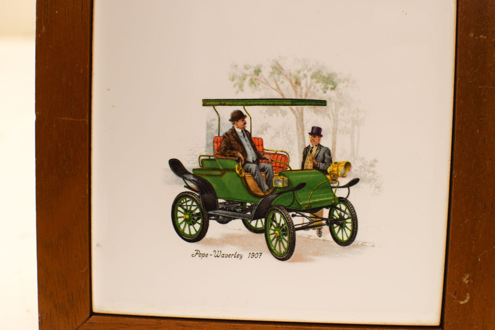 Alternative view of Wandtegel in houten lijstje met prent van  een antieke auto met 2 mannen  49841