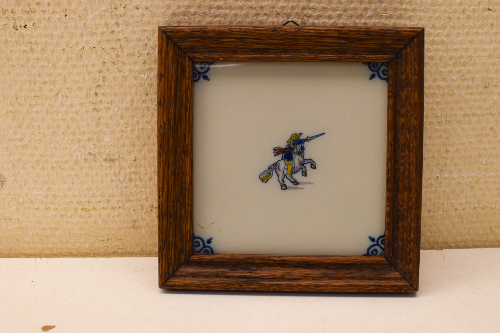 Wandtegel in houten lijstje met prent van een man met zijn zwaard op zijn paard 50599