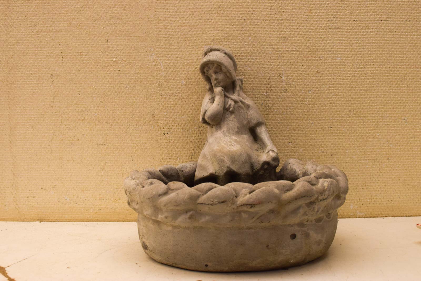 Stenen tuinbeeld met meisje zittend op de rand van de stenen mand 50865